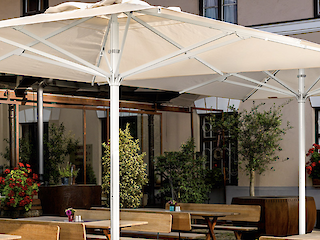 Außenbereich einer Gastroanlage mit großem Sonnenschirm