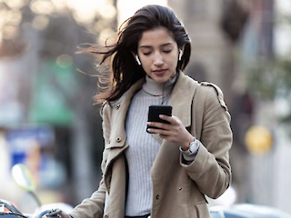 Frau schaut von unterwegs auf ihr Smartphone